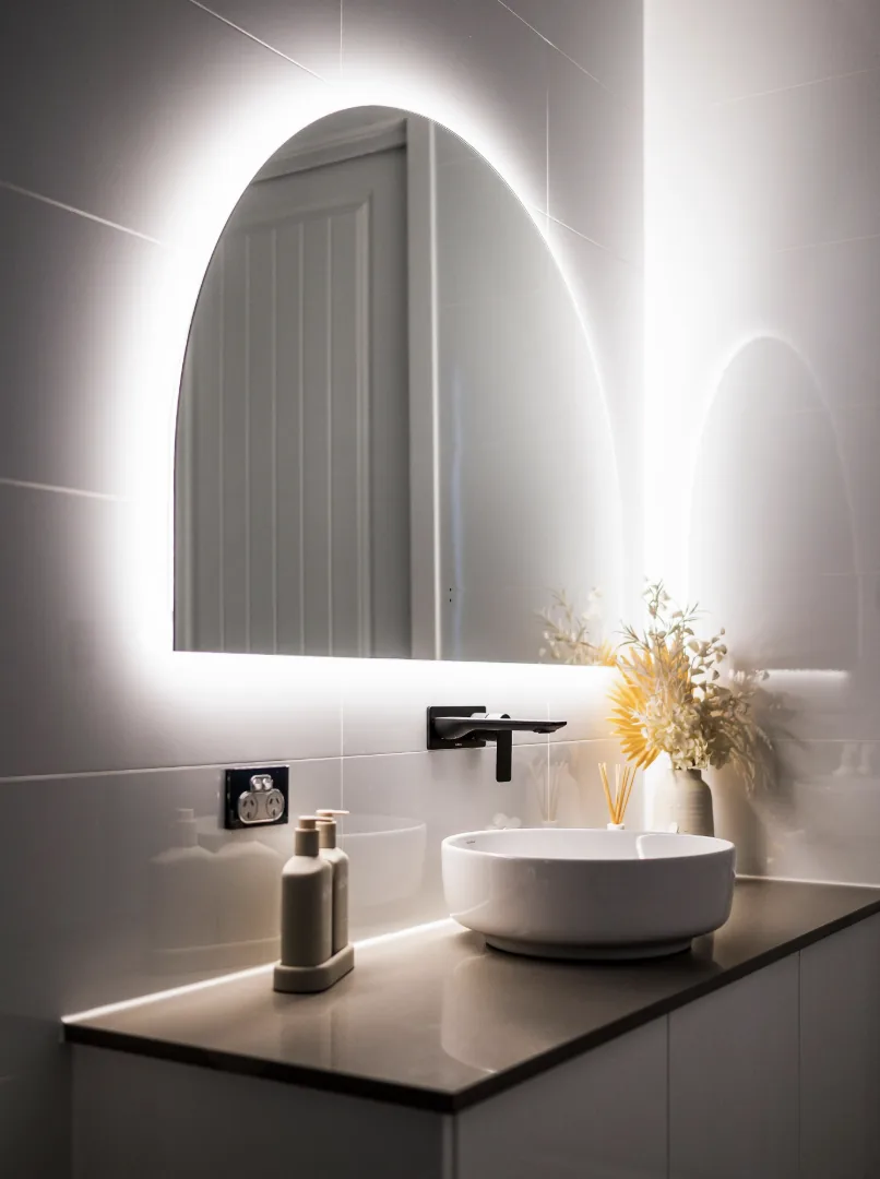 Bespoke bathroom with backlit arched mirror, stone benchtop and vessel basin