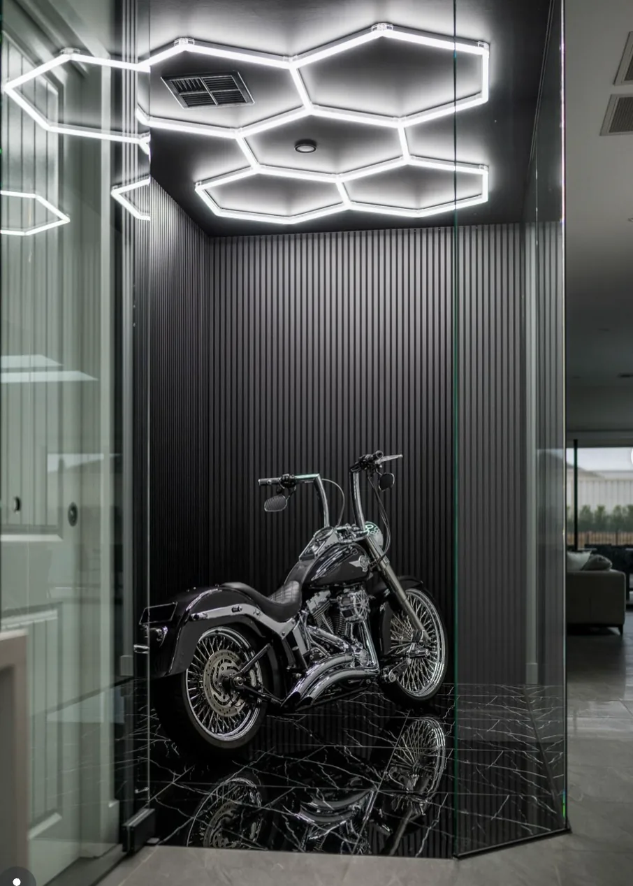 Glass walled motorcycle display room with fluted black panelling and hex lighting