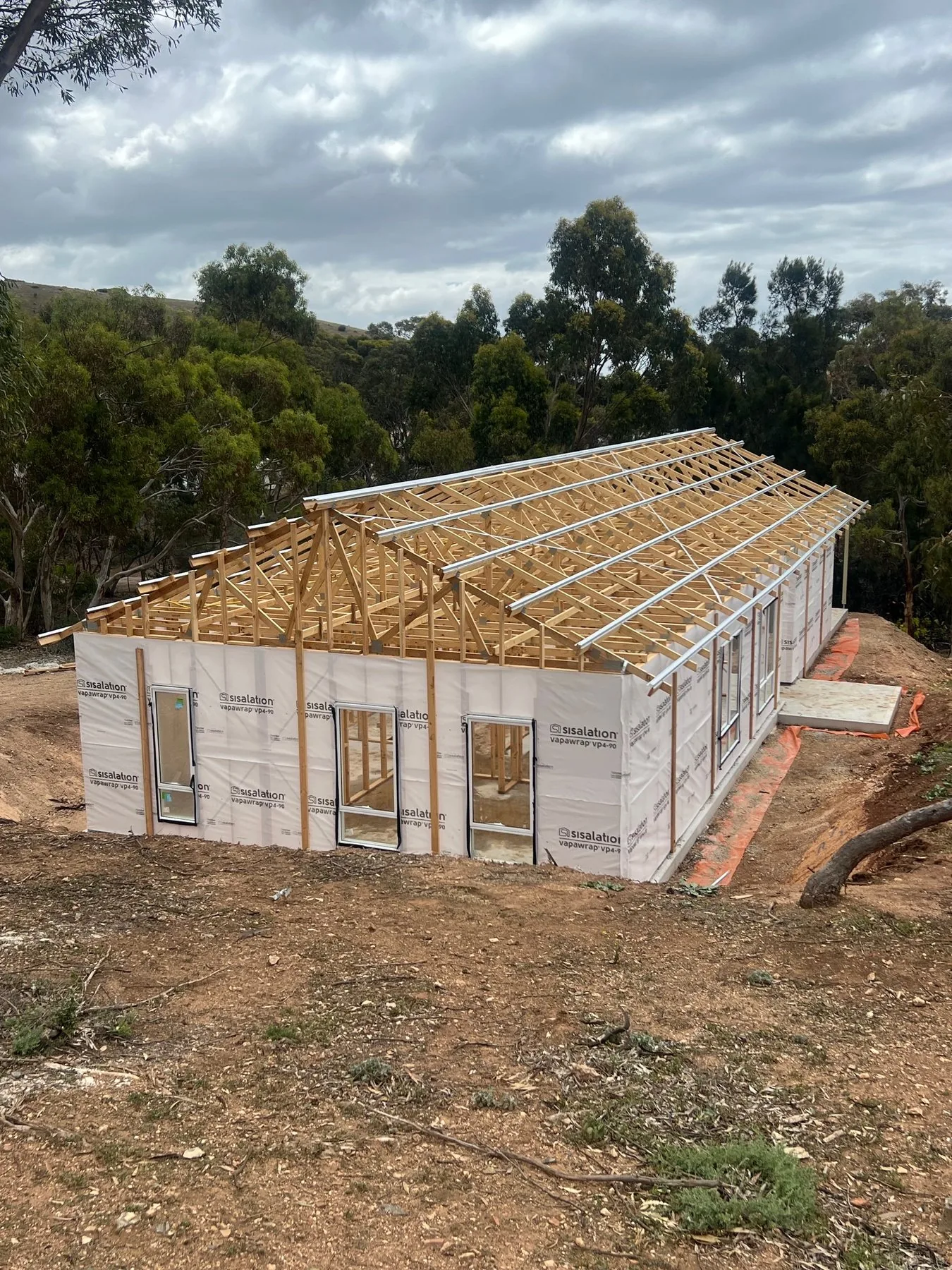 New home framed and wrapped with roof trusses up on a rural block