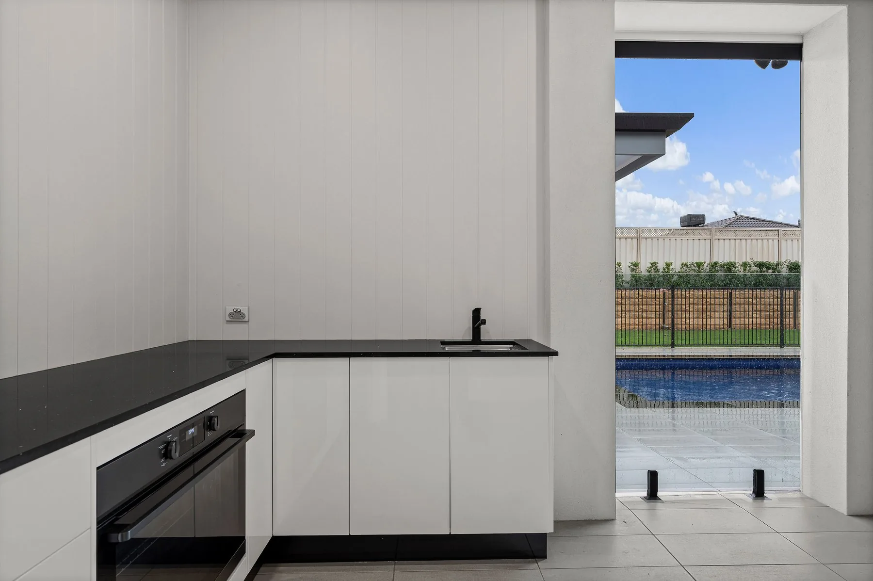 Alfresco kitchen with stone benchtop opening out to the pool deck