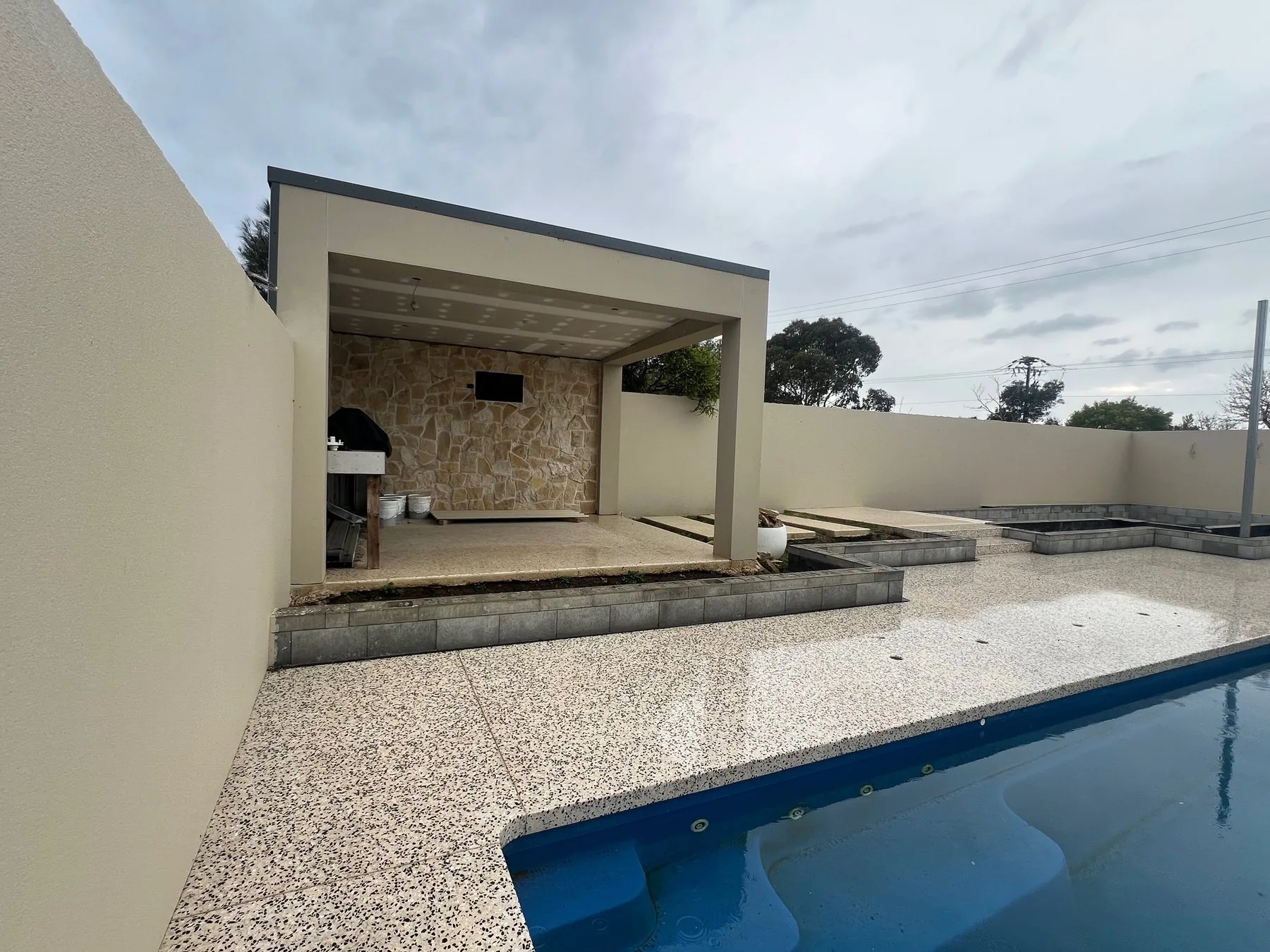 Outdoor living, Adelaide: covered pavilion beside a pool with stone feature wall